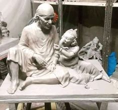 a statue of a man holding a baby sitting on top of a table next to a mirror