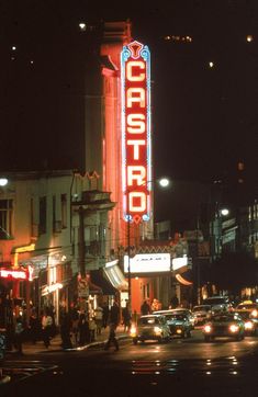 cars are driving down the street at night in front of a theater sign that reads castro