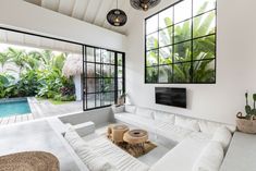 a living room filled with white furniture next to a swimming pool