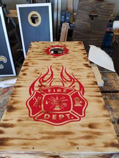 a fire department themed cornhole board on a workbench in a shop with other items