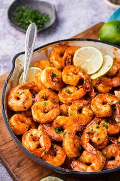 a skillet filled with shrimp and garnished with lime