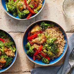 three bowls filled with rice, broccoli and chicken on top of a table