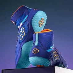 a pair of blue and orange shoes on top of a white box with purple background