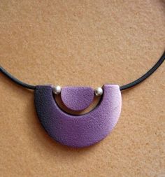 a purple necklace with two pearls hanging from it's end on a black cord