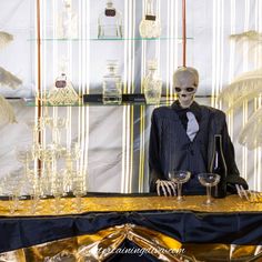 a skeleton dressed up in a suit and tie sitting at a table with wine glasses