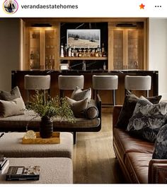 a living room filled with furniture and a bar in the back drop off wall behind it