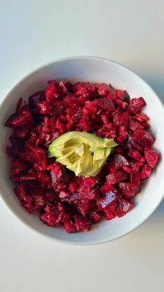 a bowl filled with beets and avocado on top of a white table