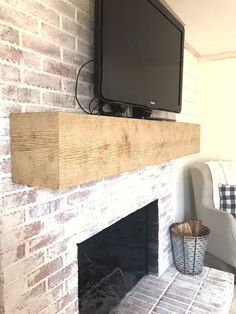 a flat screen tv mounted on top of a brick fireplace