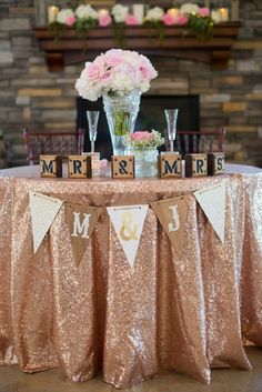 a table topped with a vase filled with flowers and two wooden blocks that say mr and mrs