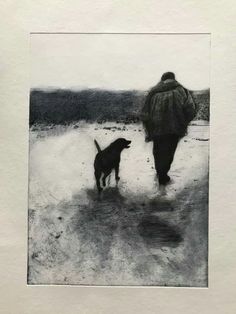 a black and white photo of a person walking with a dog on a snowy field