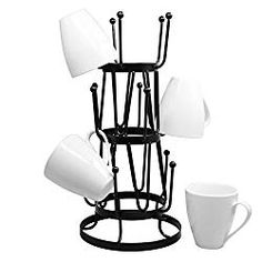 a black and white coffee cup holder with four cups on it, next to two mugs