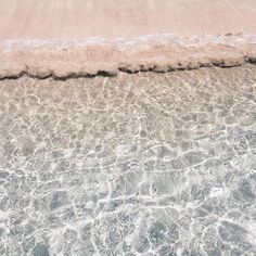 an ocean view with waves coming in from the shore and sand on the beach below