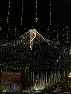 the lights are hanging from the ceiling in the city street at night, with cars driving by