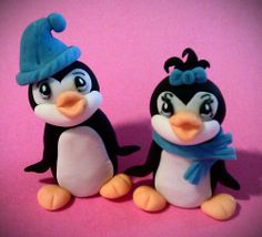 two plastic penguins with hats and scarves on their heads sitting next to each other