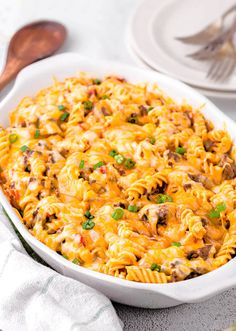 a casserole dish with meat and cheese in it on a table next to silverware