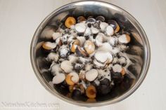 a metal bowl filled with lots of food on top of a white tablecloth covered floor