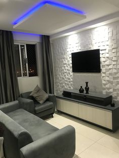 a living room with two gray couches and a flat screen tv on the wall