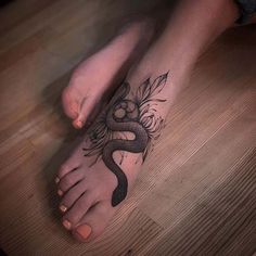 a woman's foot with a snake tattoo on it