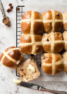 a bunch of hot cross buns sitting on top of a cooling rack next to a knife