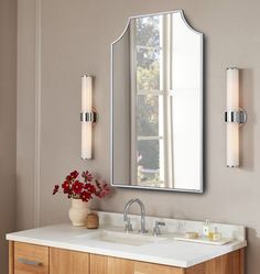 a bathroom vanity with a mirror above it and two lights on the wall next to it