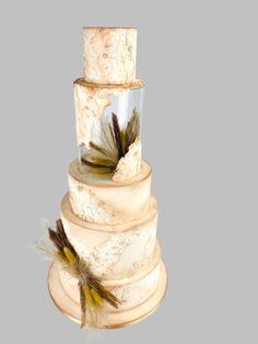 a three tiered cake with feathers on top