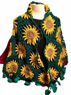 a green and yellow crocheted shawl with sunflowers on the front