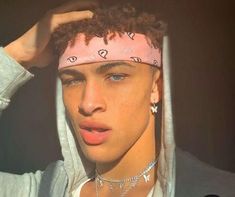 a young man wearing a pink bandana with hearts on it's head and piercings around his ears