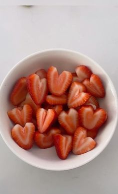 a white bowl filled with sliced strawberries on top of a table