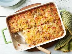 a casserole dish is shown with a serving spoon and napkin on the side