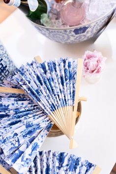 blue and white paper fans sitting on top of a table next to a vase with flowers