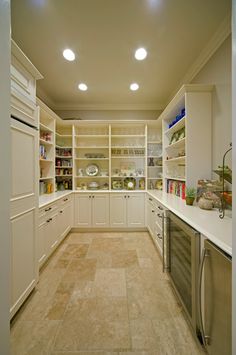 an empty kitchen with white cabinets and marble flooring