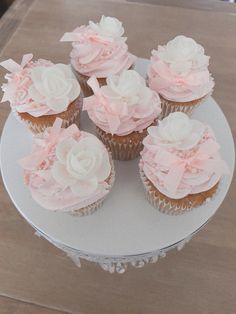 several cupcakes with pink frosting on a white plate