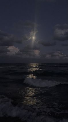 the moon is shining over the ocean with dark clouds and waves in the foreground