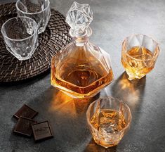 three glasses and one bottle on a table with some chocolates next to it in front of them