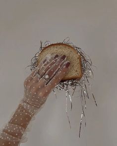 a woman's hand holding up a piece of bread with nails on top of it