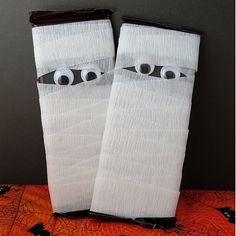 two white socks with eyes on them sitting on top of an orange cloth covered table