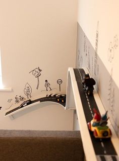 a toy train set sitting on top of a wooden table next to a wall with writing on it