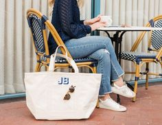 a woman sitting at a table with a tote bag on her lap and coffee in front of her