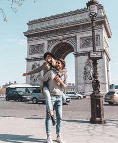 a man and woman walking in front of the arc de trioe