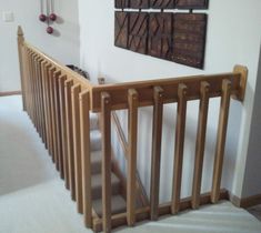 there is a wooden stair case in the house with pictures on the wall behind it