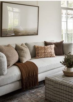 a living room filled with lots of furniture and pillows on top of a couch next to a window