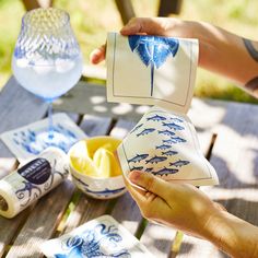 two hands are holding blue and white plates with designs on them, while another hand holds a napkin