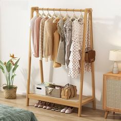 a wooden rack with clothes and shoes on it in a bedroom next to a bed