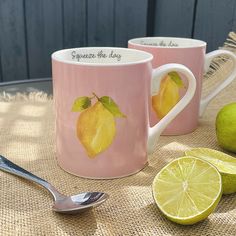 two coffee mugs with lemons and limes on a table