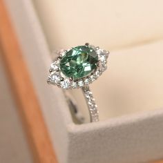 a ring with a green stone surrounded by diamonds