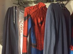 clothes hanging on racks in a closet with spider - man hoodies and sweatshirts