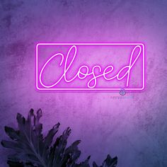 a purple neon sign that says closed on the side of a wall next to a plant