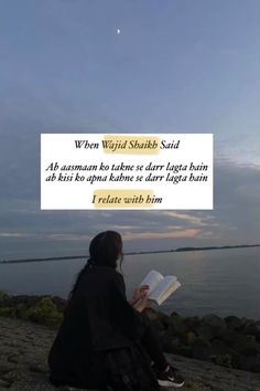 a woman sitting on top of a rocky beach next to the ocean reading a book