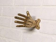 a gold hand is attached to a white brick wall