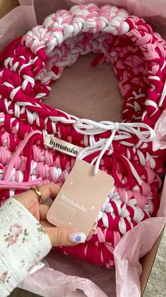 a pink and white crocheted wreath with a tag